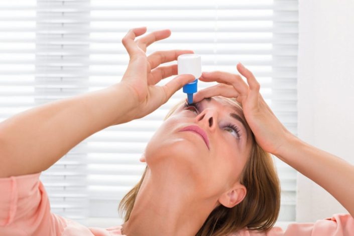 woman putting medicine in her eyes
